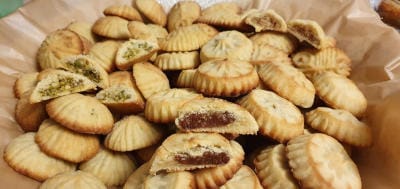 أقراص معمول في صحن، منها أقراص مقسومة تظر حشوتها و أخرى غير مقسومة.