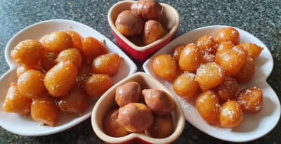 كرات بنيّة (عوامة) في أربعة صحون بشكل قلوب. جوف الصحون أبيض. في صحنين العوامة عليها شكولاتة و في واحد من الصحون عليها جوز هند.